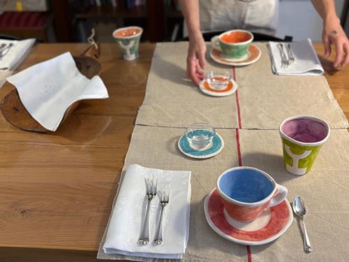 a wooden table with plates and cups and utensils at Museo Grillo Camere d'Arte, dormire nel Museo in Arena Po