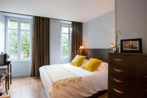 una camera da letto con un letto con due cuscini gialli di Les Chambres de L'Ecrit'Vin - En plein coeur du centre-ville a Beaune