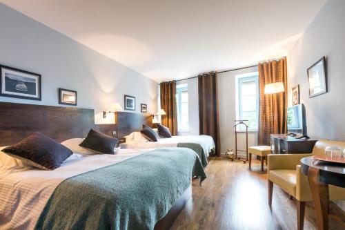 una camera d'albergo con due letti e un tavolo di Les Chambres de L'Ecrit'Vin - En plein coeur du centre-ville a Beaune