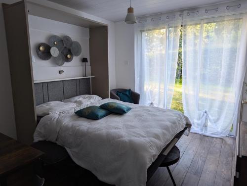 une chambre avec un lit aux oreillers bleus et une fenêtre dans l'établissement Au coeur des rias, studio Bélon, proche de la mer, à Moëlan-sur-Mer