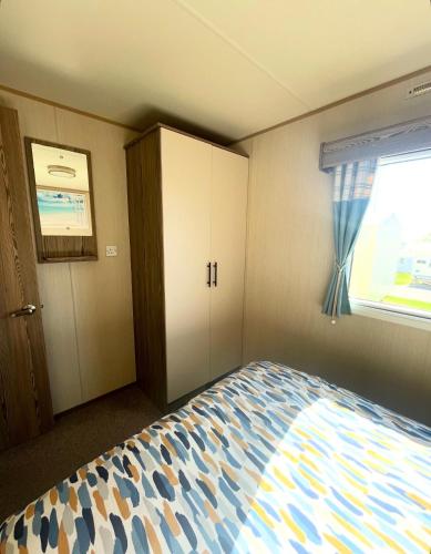 a small bedroom with a bed and a window at Golden Sands Getaways Weymouth in Wyke Regis