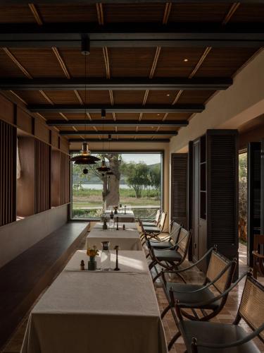 a dining room with tables and chairs and a large window at 大理空山语 风眠艺术海景酒店 Dali Kongshanyu Art Seaview Hotel in Dali Airport