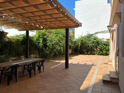 a patio with tables and chairs under a wooden pergola at Chalet San Francisco in Sanlúcar de Barrameda