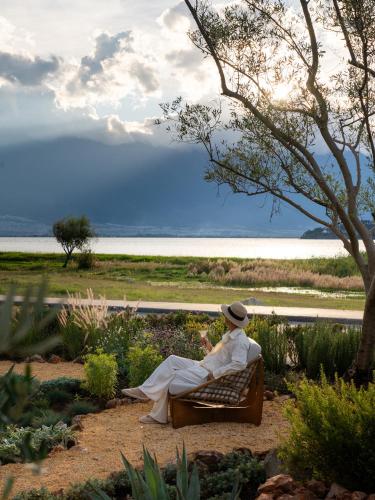 a woman sitting on a bench near the water at 大理空山语 风眠艺术海景酒店 Dali Kongshanyu Art Seaview Hotel in Dali Airport