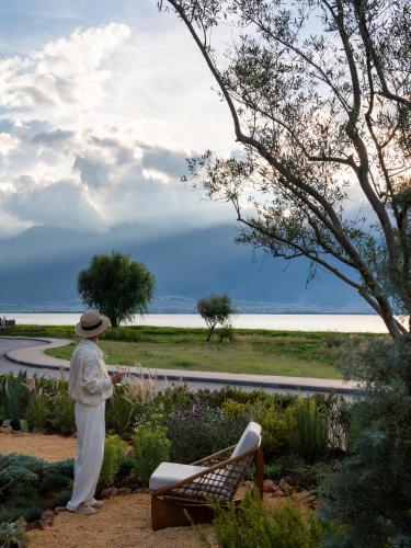 a man standing in a garden looking at the water at 大理空山语 风眠艺术海景酒店 Dali Kongshanyu Art Seaview Hotel in Dali Airport
