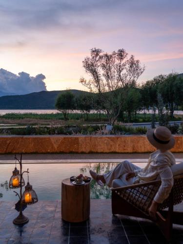 a woman sitting on a bench next to a pool at 大理空山语 风眠艺术海景酒店 Dali Kongshanyu Art Seaview Hotel in Dali Airport