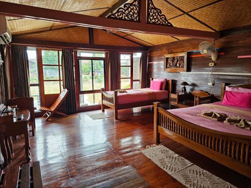a bedroom with two beds in a room with wooden walls at Kanecha's Home Lampang in Lampang
