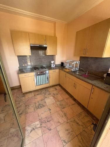 a kitchen with wooden cabinets and a tiled floor at Appartement standing piscine la palmeraie in Marrakech