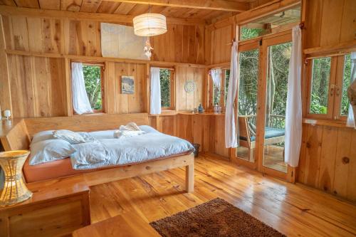 una camera da letto con un letto in una casa di legno di Venga Atitlan a San Marcos La Laguna
