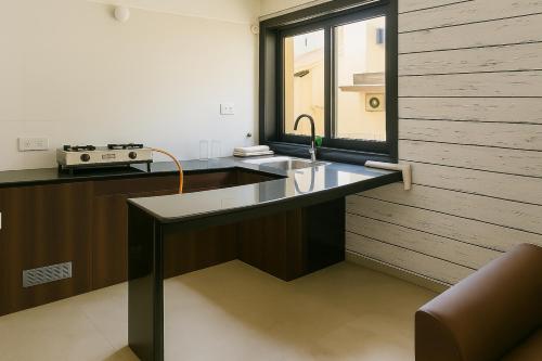 a kitchen with a counter with a sink and a window at LUXY Service Apartment at North GOA in Calangute