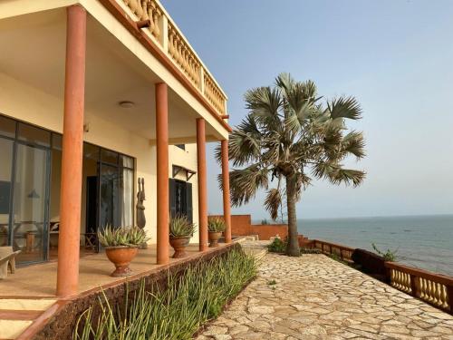a building with a palm tree next to the ocean at Terrasse Maisonnette Chambre jardin in Rufisque