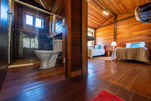a bathroom with a toilet in a wooden cabin at Pousada Refúgio do Leão in Camanducaia