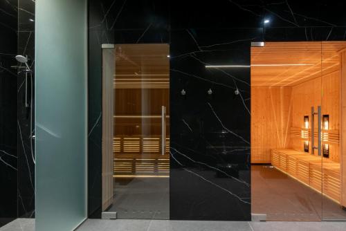 a bathroom with black marble walls and a glass door at Baltic Infinity Resort&Spa Apartament Dworek in Międzyzdroje