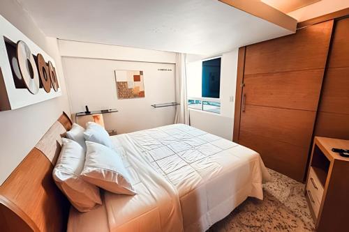 a bedroom with a white bed and a wooden door at Cobertura em Hotel de Luxo na Beira Mar in Natal