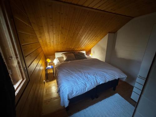 a bed in a room with a wooden ceiling at Villa Vanttaja in Kuusamo