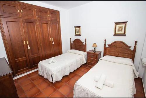 a bedroom with two beds and wooden cabinets at Casa Rural El Valle in Torre de Miguel Sesmero