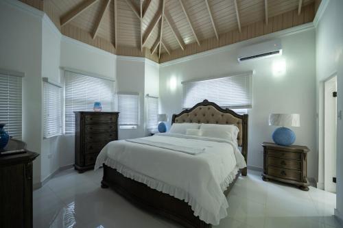 a bedroom with a large bed with white walls and windows at Tuscany Sunville in Montego Bay