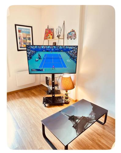 a large computer monitor in a living room with a table at Grand T2 tout confort 48 M2 - Offre cinéma et sport canal séries, netflix, Dazen, eurosport, apple TV, OCS, paramount, prime vidéo in Nancy