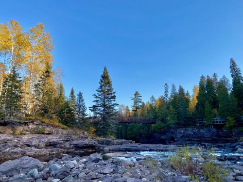 a bridge over a river in the woods at Gooseberry Trailside Suites by Heirloom Boutique Collection in Two Harbors