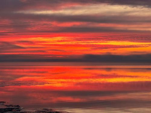 a sunset over the water with clouds in the sky at Gooseberry Trailside Suites by Heirloom Boutique Collection in Two Harbors