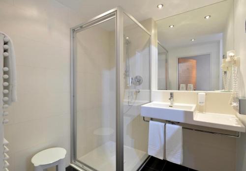 Un baño blanco con ducha y lavabo. en Hotel TA Sololaki, en Tiflis
