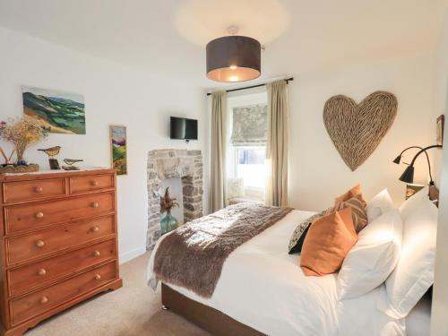ein Schlafzimmer mit einem Bett, einer Kommode und einem Fenster in der Unterkunft Gosling Cottage in Kendal
