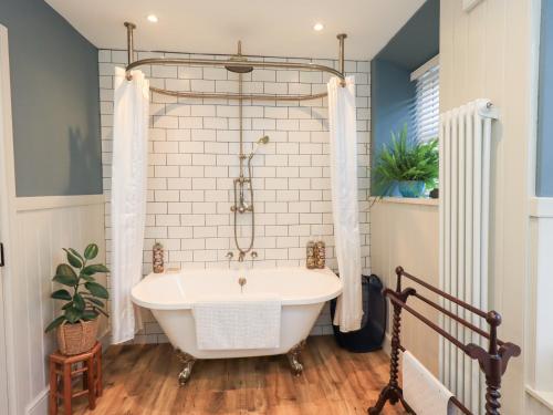 eine weiße Badewanne in einem Badezimmer mit Fenster in der Unterkunft Gosling Cottage in Kendal