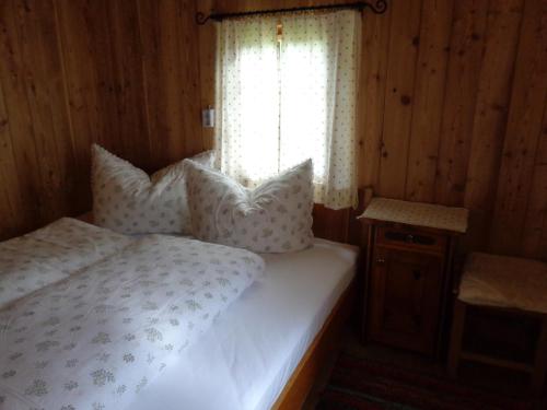 Un dormitorio con una cama con almohadas y una ventana. en Tauhäusl, en Innervillgraten