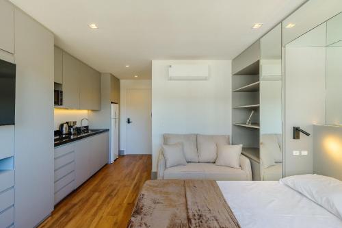 a bedroom with a bed and a chair and a kitchen at Novíssimo: Go Carlos Gomes - Infra estrutura e Vista Espetacular! in Porto Alegre
