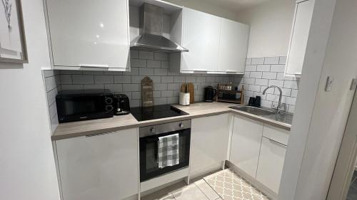 a kitchen with white cabinets and a black microwave at Chic & Comfy 1 Bed Apartment Sheffield Stay in Midland