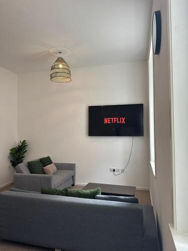 a living room with a couch and a tv on the wall at Chic & Comfy 1 Bed Apartment Sheffield Stay in Midland