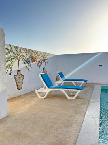 a pair of blue chairs next to a swimming pool at Dar tannich in Erriadh