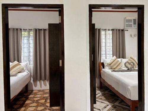 two beds in a room with two windows at Blue House El Nido in El Nido
