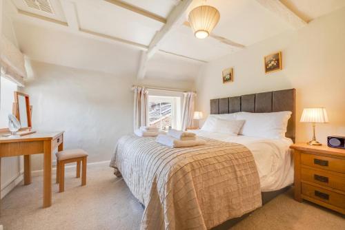 a bedroom with a bed and a desk and a window at Pear Tree Cottage in Blakeney