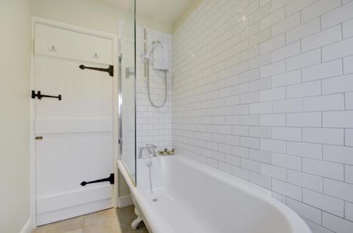 a white bathroom with a tub and a shower at Pear Tree Cottage in Blakeney