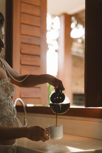 a woman is pouring coffee into a tea pot at Villa Binn Preá in Prea