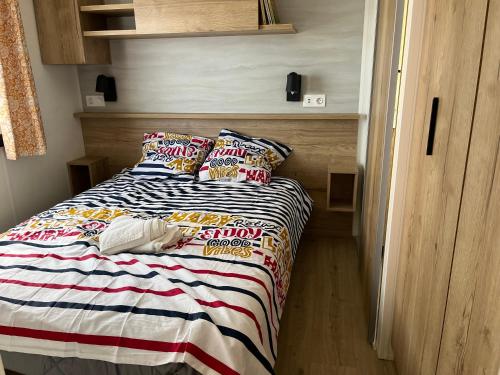 a small bedroom with a bed with a colorful blanket at MH 399 3 chambres et 2 salles de bain entièrement équipé dans camping 4 étoiles in Saint-Julien-en-Born