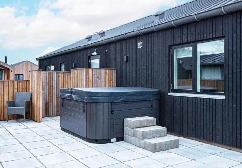 a black building with a hot tub on a patio at SJ302-Haderslev-Blokhusskoven-63 in Kelstrup Strand