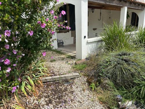 un jardin avec des fleurs roses à côté d'une maison dans l'établissement Chez Aurélie & Mathieu studio dans ancienne maison rénovée proche du Lac, à Dompierre-sur-Yon