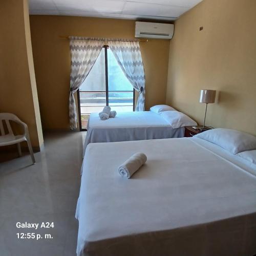 two beds in a hotel room with a window at Suites Sonikikos in Ballenita