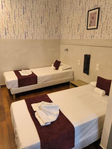 a room with three beds with towels on them at Hôtel Abalone - Centre Gare in Nîmes