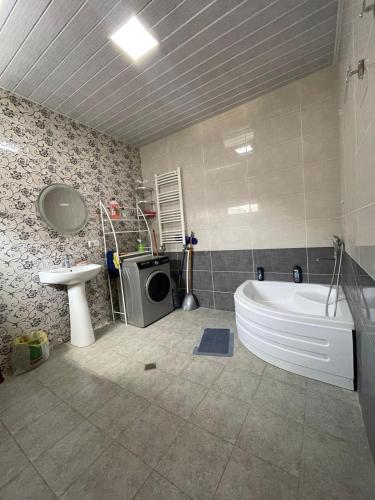 a bathroom with a tub and a sink and a washing machine at Happy Rustavi guest house in Rustavi