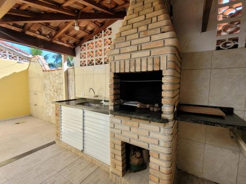 a brick oven in a kitchen with a fireplace at Casa para Temporada na Morada da Praia em Bertioga SP in Bertioga