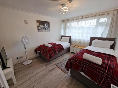 a bedroom with two beds and a fan at NightRest Homes Smart TV In Each Room - Parking - Hemel Hempstead in Hemel Hempstead
