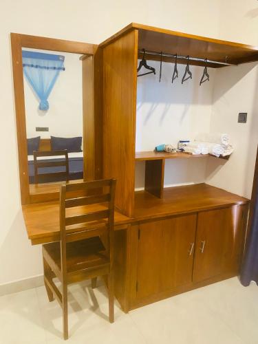 a wooden cabinet with a chair and a mirror at Hotel Hanguk Villa in Dambulla
