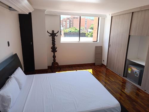 Un dormitorio con una cama blanca y una ventana. en De vuelta al sol, en Medellín