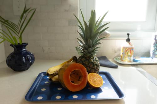 a blue plate with a pineapple and a papaya on a counter at Signature's Dorado Relaxing Villa in Dorado