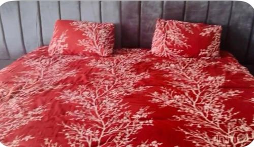 a bed with a red comforter and two pillows at Graceville Haven in Abeokuta