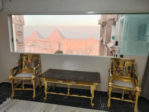 a table and two chairs with a view of the pyramids at Pyramids Gate in Giza