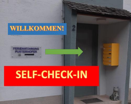 a sign that says self check in and a cat sitting outside a building at Studio Wildwiese Rettenegg in Rettenegg